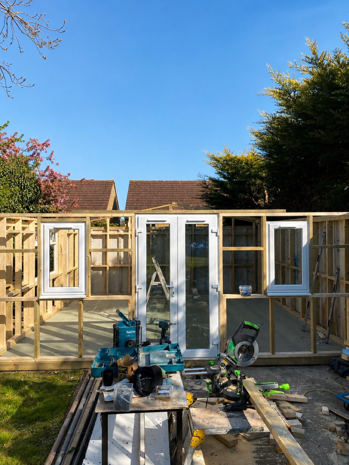 A new timber frame and glazing going up on the slab during a garden studio build.